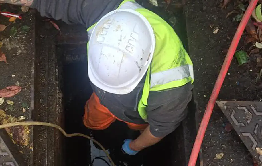 Drainage engineer accessing an underground chamber to carry out drainage inspection and maintenance work.