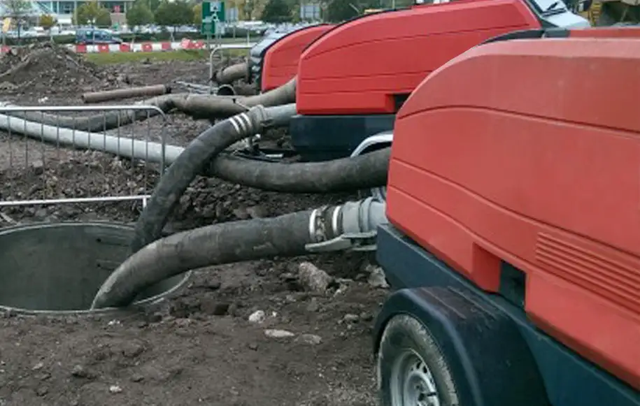 Over pumping equipment diverting wastewater flow through temporary bypass pipes during drainage works.
