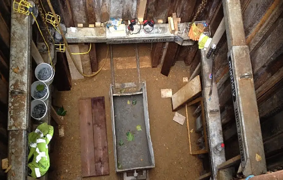 Deep excavation for sewer connections and headings with trench support systems installed for safe access.