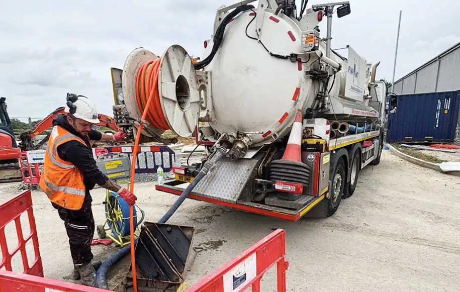 Vacuum tanker removing wastewater and debris from a drainage chamber during drainage maintenance works.